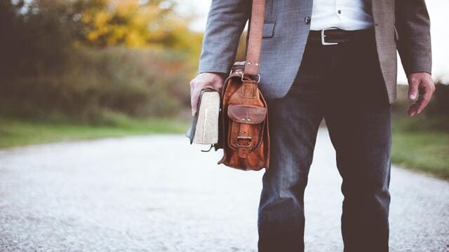 رجل يرتدي بذلة رسمية وحقيبة ويمسك كتاب