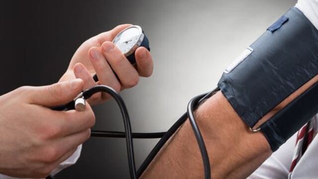 يد شخص تمسك بجهاز قياس ضغط الدم ويقيس الضغط لشخص اخر