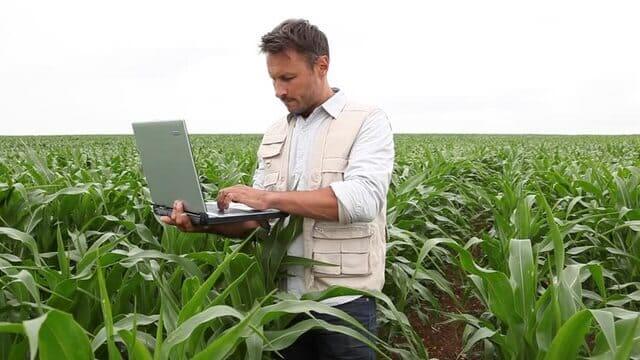 مهندس زراعي يمسك بحاسوب شخصي ويقف في المزرعة